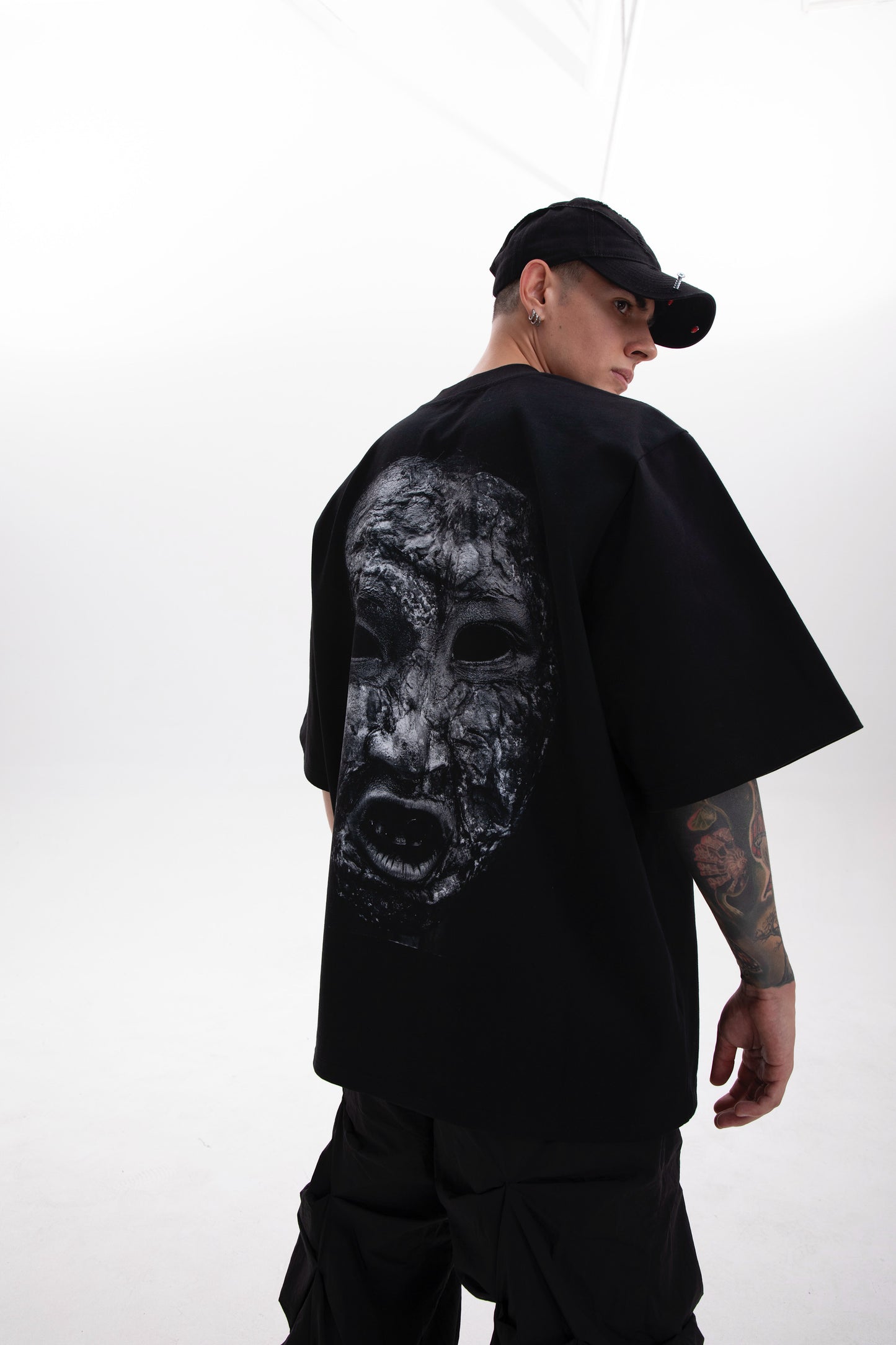 Model wearing the Toneface back print black tee in a dark aesthetic outfit on a white background