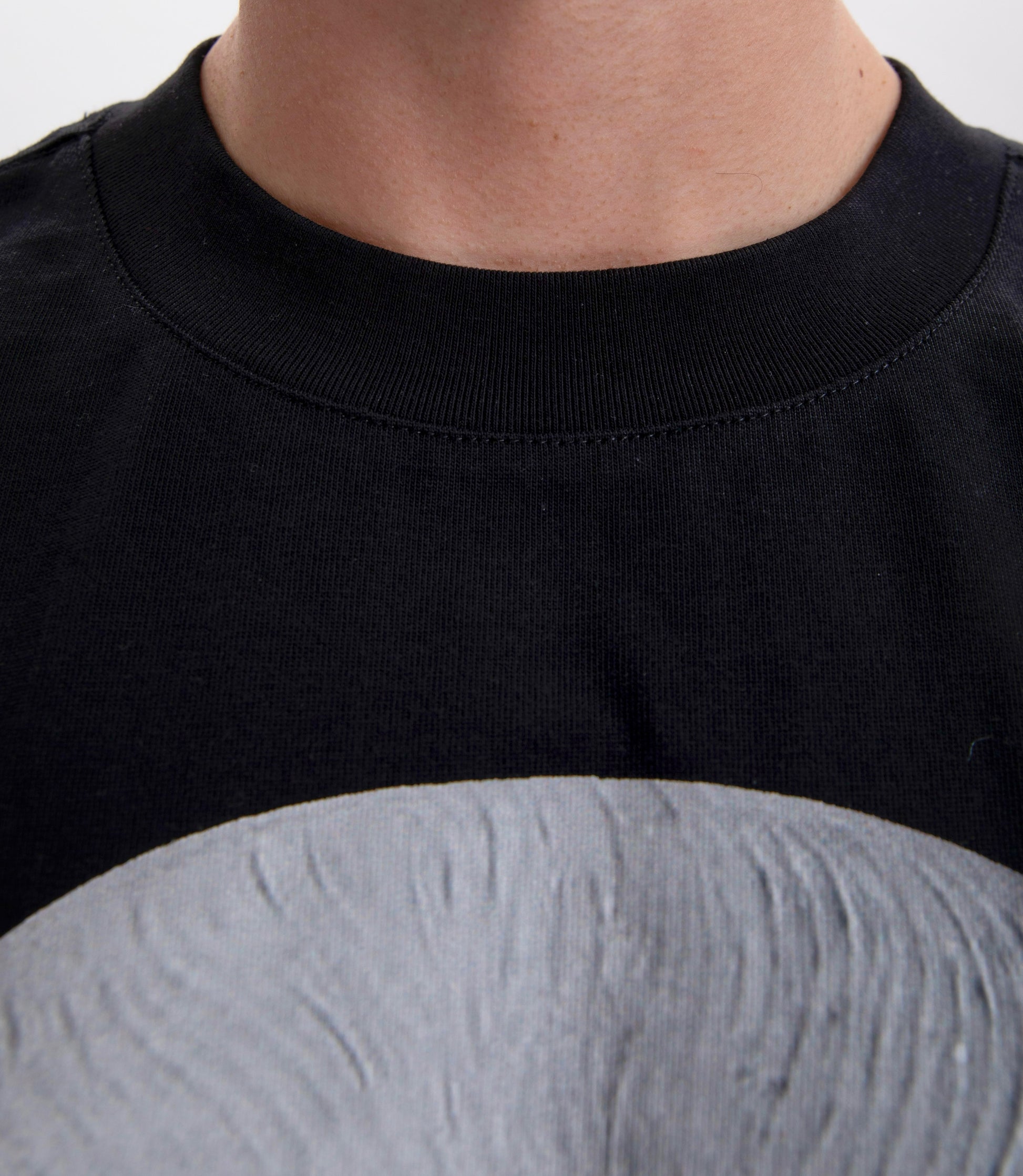 Close-up of a black BYOG  t-shirt with a focus on the collar and neckline.