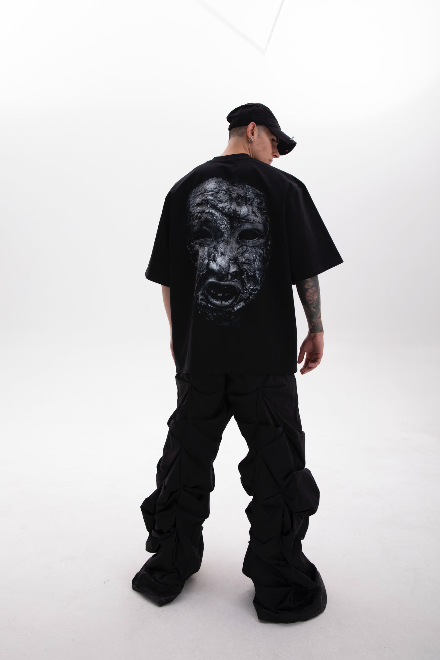 Model wearing the Toneface back print black tee in a dark aesthetic outfit on a white background