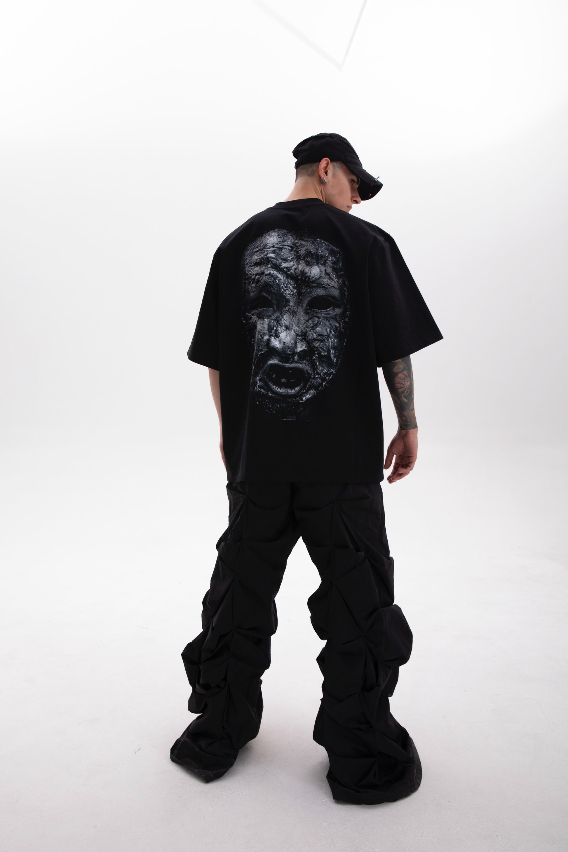 Model wearing the Toneface back print black tee in a dark aesthetic outfit on a white background