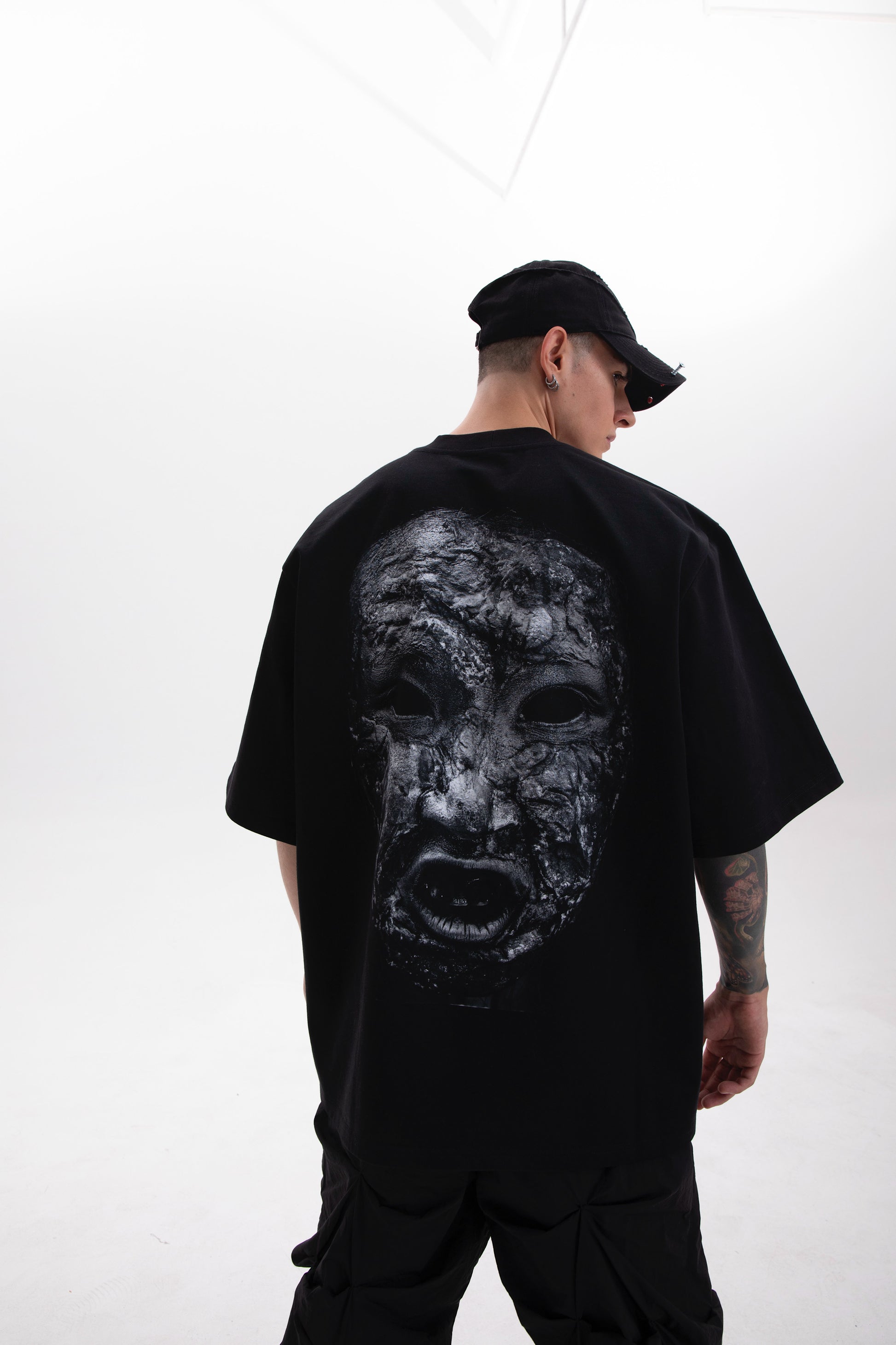 Model wearing the Toneface back print black tee in a dark aesthetic outfit on a white background