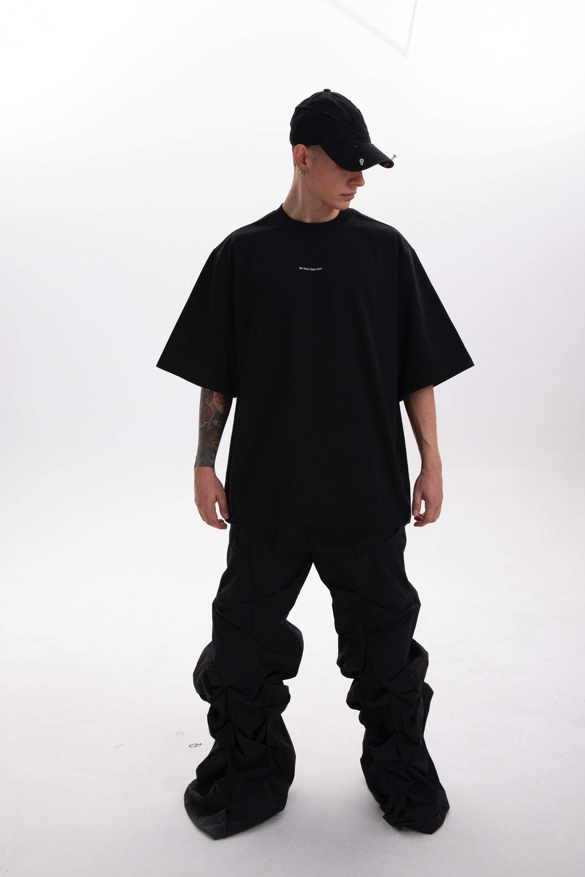 Model wearing the Be Your Own God black heavyweight tee with minimal front print on a white background