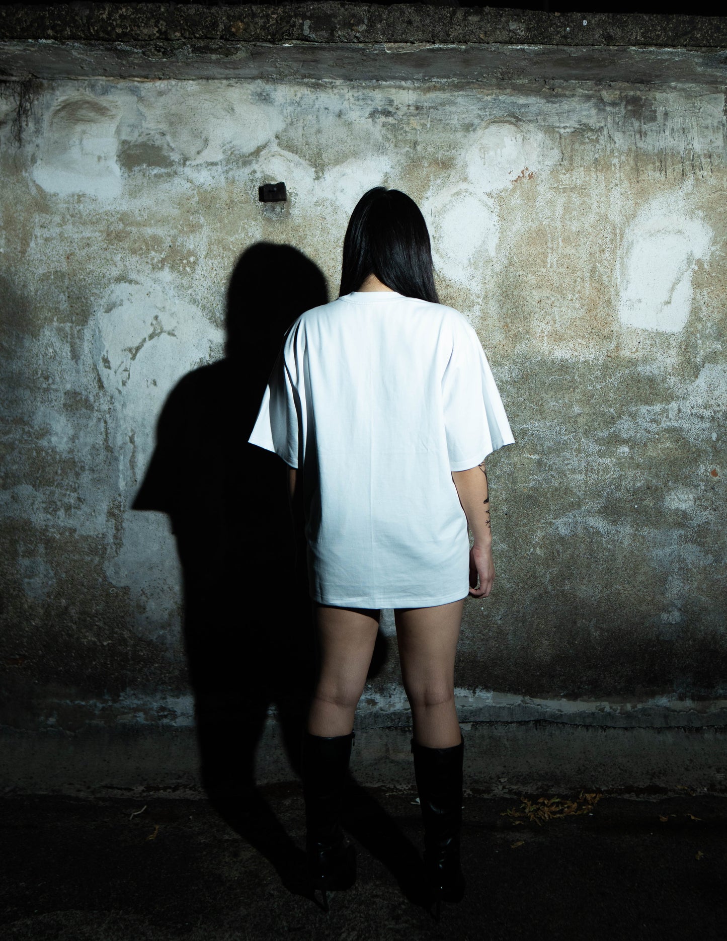 Person wearing a white t-shirt against a textured wall
