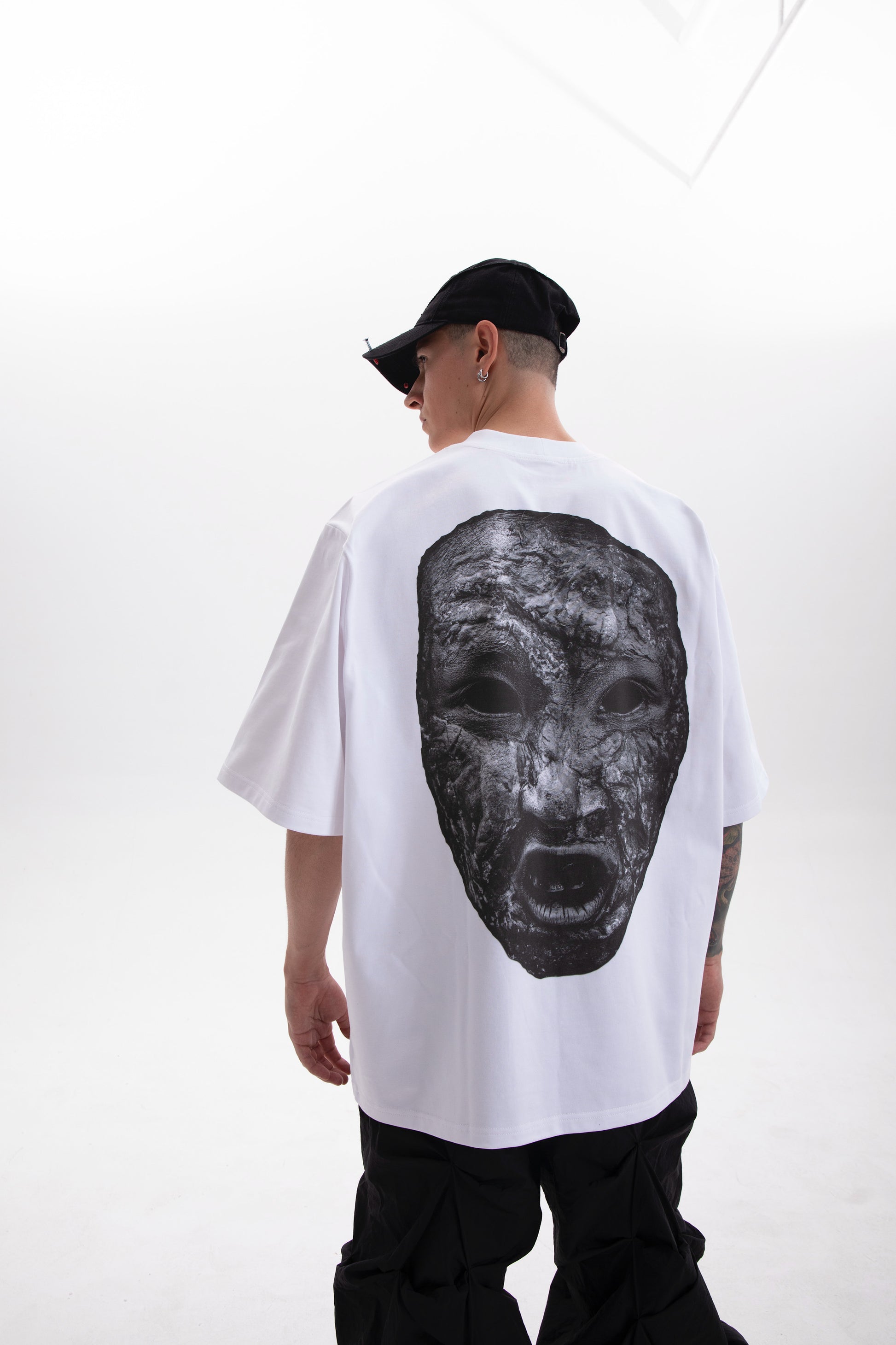 Model wearing the white Stoneface back print t-shirt styled in a dark aesthetic outfit on a white background