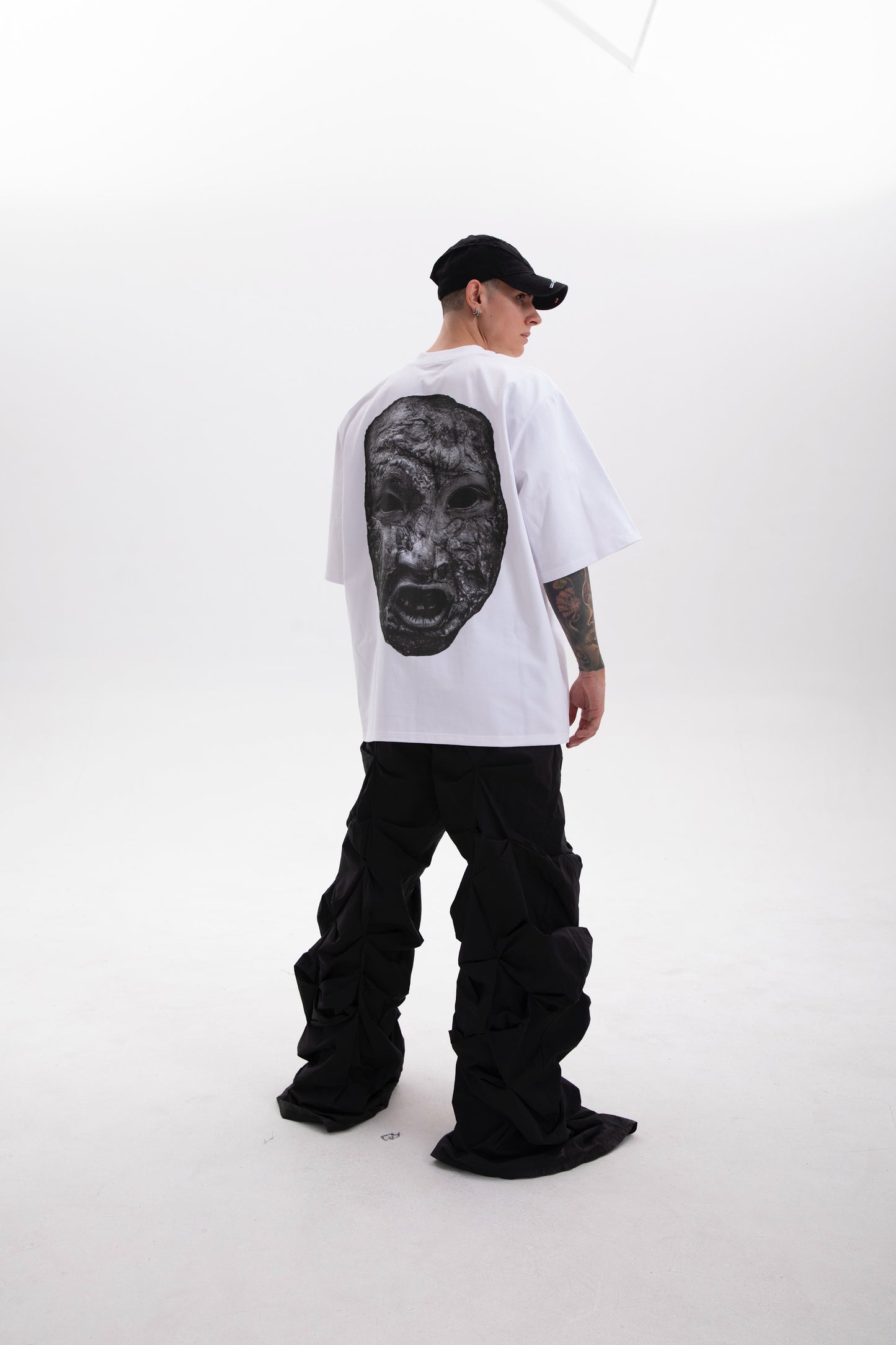 Model wearing the white Stoneface back print t-shirt styled in a dark aesthetic outfit on a white background